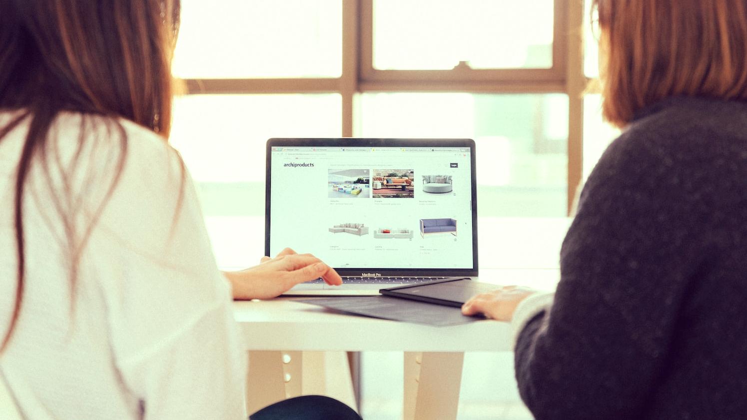 two women talking while looking at laptop computer